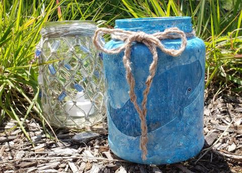a painted jar lantern and a knotted jar lantern sitting on the ground