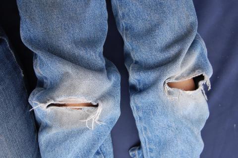 close-up of jeans with tears at both knees