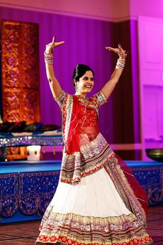 Picture of smiling Jaya Mathur with both her arms up in a Bollywood dance pose.
