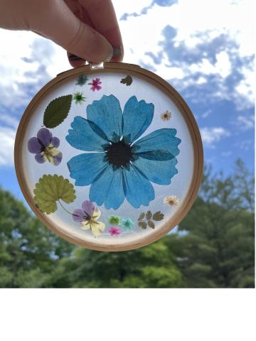 an embroidery hoop filled with pressed flowers and leaves