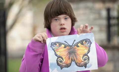 Teen with brown short hair holding a butterfly painting