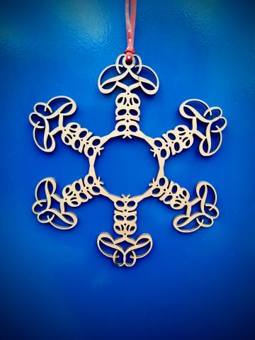 Wooden snowflake with reflections and tessellations of the word "Read" against a blue background