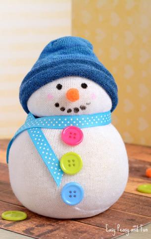 Photo of a snowman in front of a background with snow and pine trees titled Create by Music at the top and at the bottom No-Sew Sock Snowpeople.