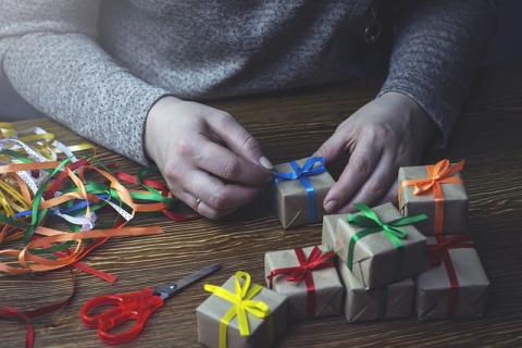 hands wrapping small gifts on a table