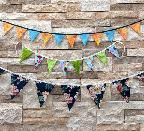 three rows of colorful fabric triangles against a stone wall