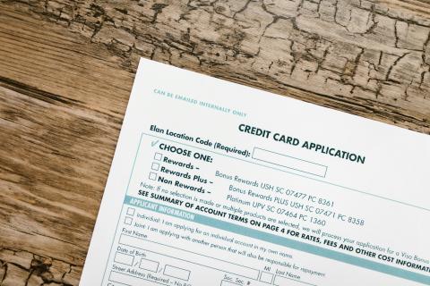 piece of paper titled 'credit card application' on a wood table