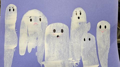 a collection of white ghosts with black eyes and mouths, painted on blue paper