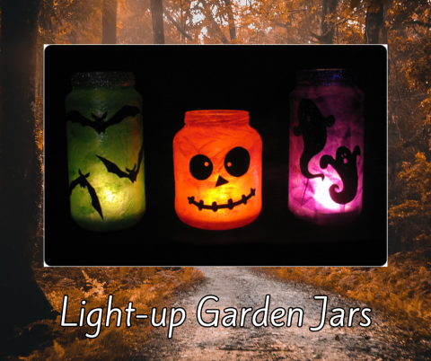 Three light-up garden jars with Halloween-themed designs. The left jar is green with black bat silhouettes, the middle jar is orange with a jack-o'-lantern face featuring round eyes and a stitched mouth, and the right jar is purple with black silhouettes of a ghost and a cat. Text below the jars reads 'Light-up Garden Jars.'