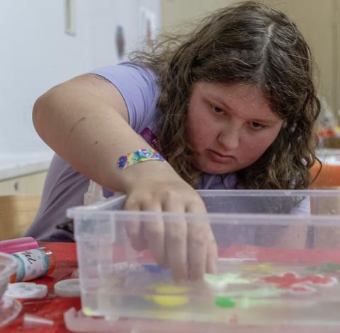 Teen reaching into sensory bin - HCLS Flickr