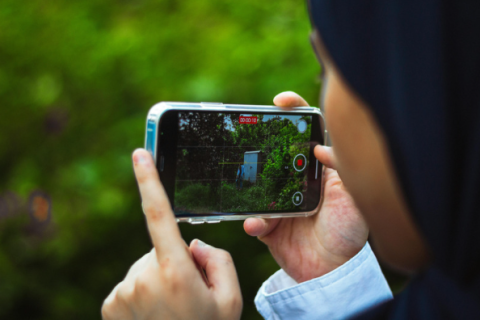 An over the shoulder shot of a person filming greenery on their phone
