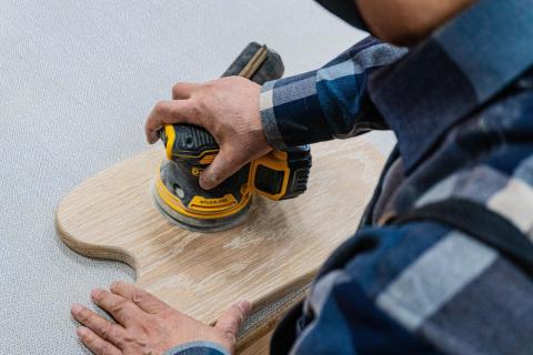 a hand sanding a wood cutting board