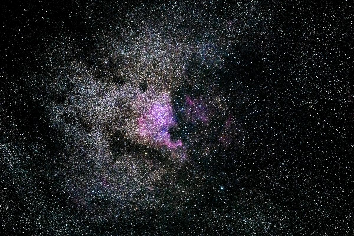 Photo of galaxy with black cosmos and central purple light.