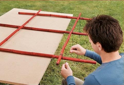 man lashing bamboo poles together