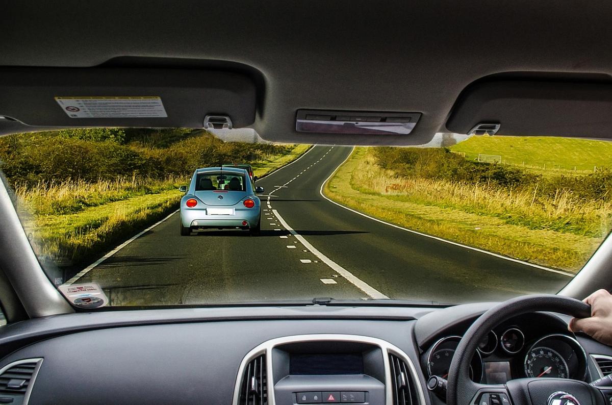 A driver taking a drive on a country road. Only one other car is on the road.