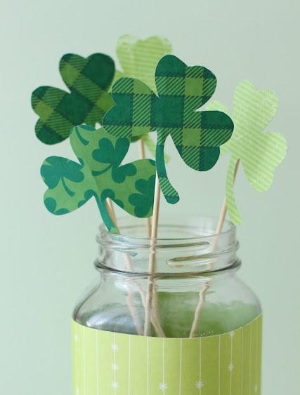 Mason jar with cut out shamrocks on bamboo skewers.