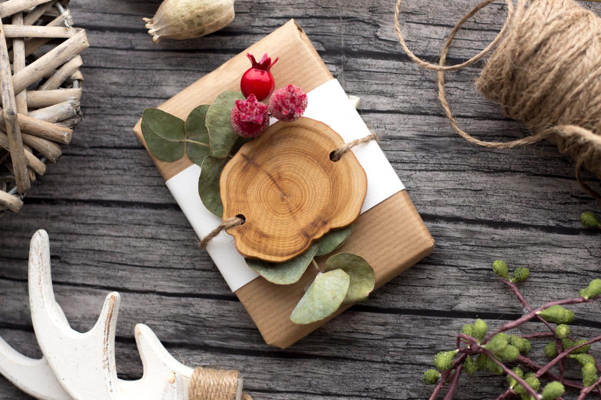 package wrapped in brown paper and twine with slice of wood and leaves decorating it