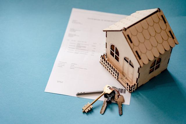 blue background with a small wooden cabin, a white paper and a set of home keys