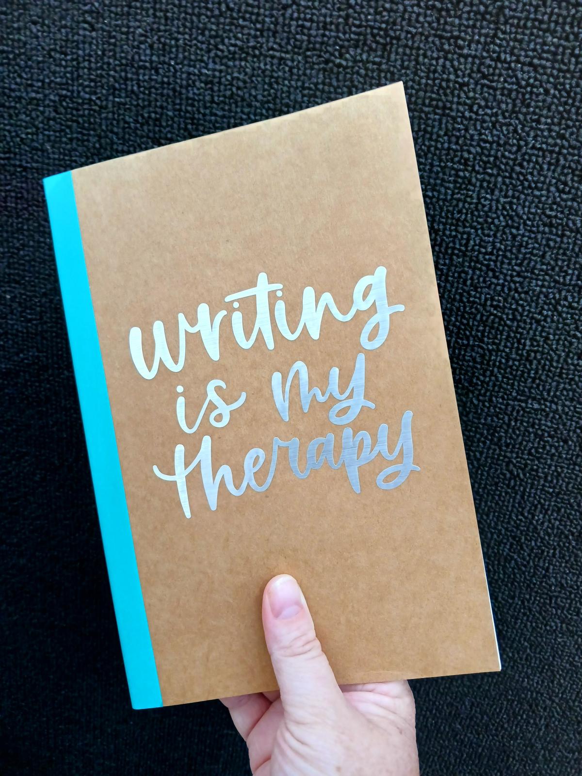 Kraft colored notebook cover labeled "Writing is my therapy"