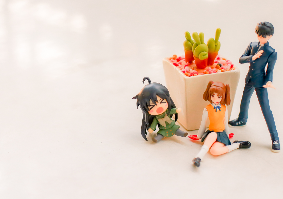 three anime figurines sat around a potted succulent