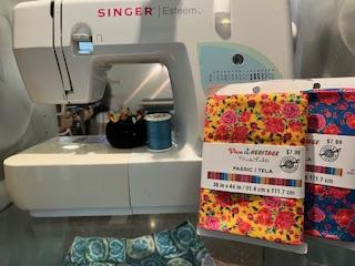 singer sewing machine with two colored floral fabric bundles with yellows, pinks and blues