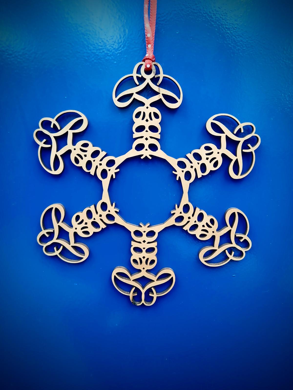 Wooden snowflake with reflections and tessellations of the word "Read" against a blue background