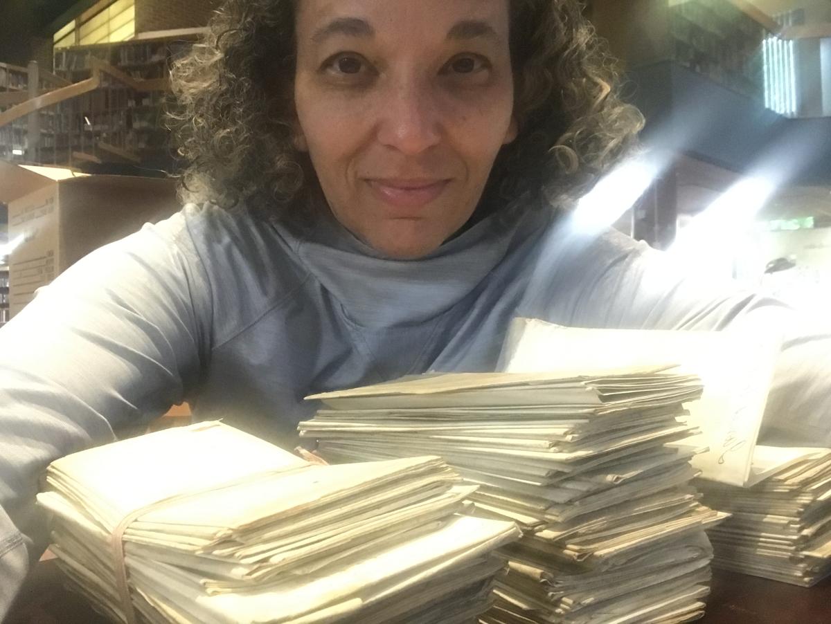 a woman smiles behind a pile of documents