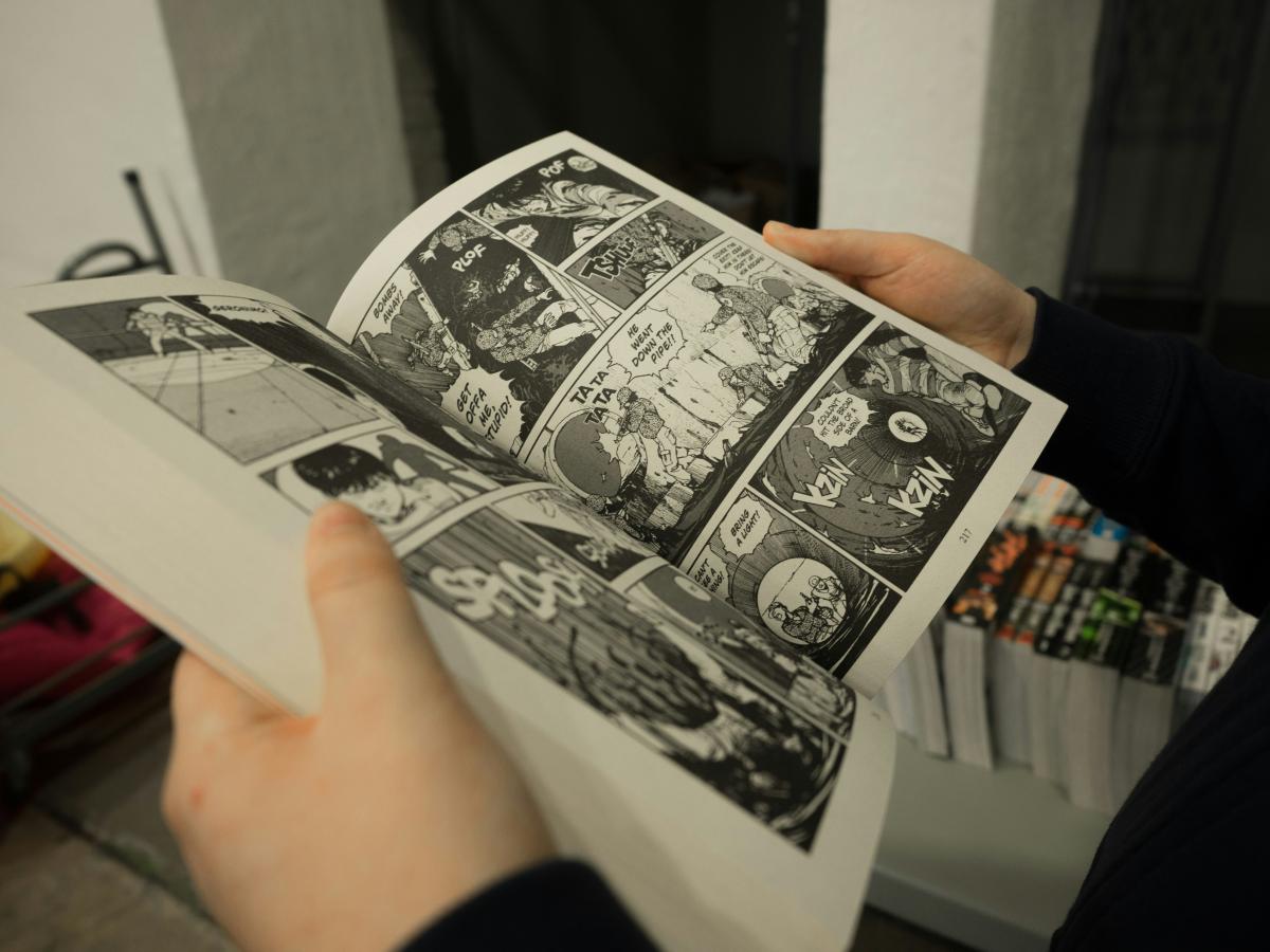 An open volume of black and white manga being held by a reader