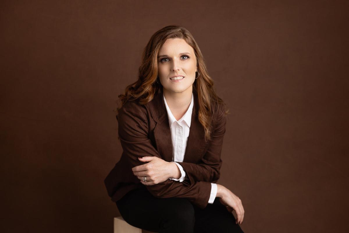 Ann Bennett sits facing the camera, wearing brown
