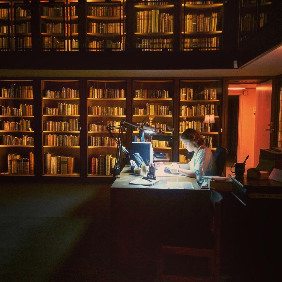 Woman working in library with stacks behind her