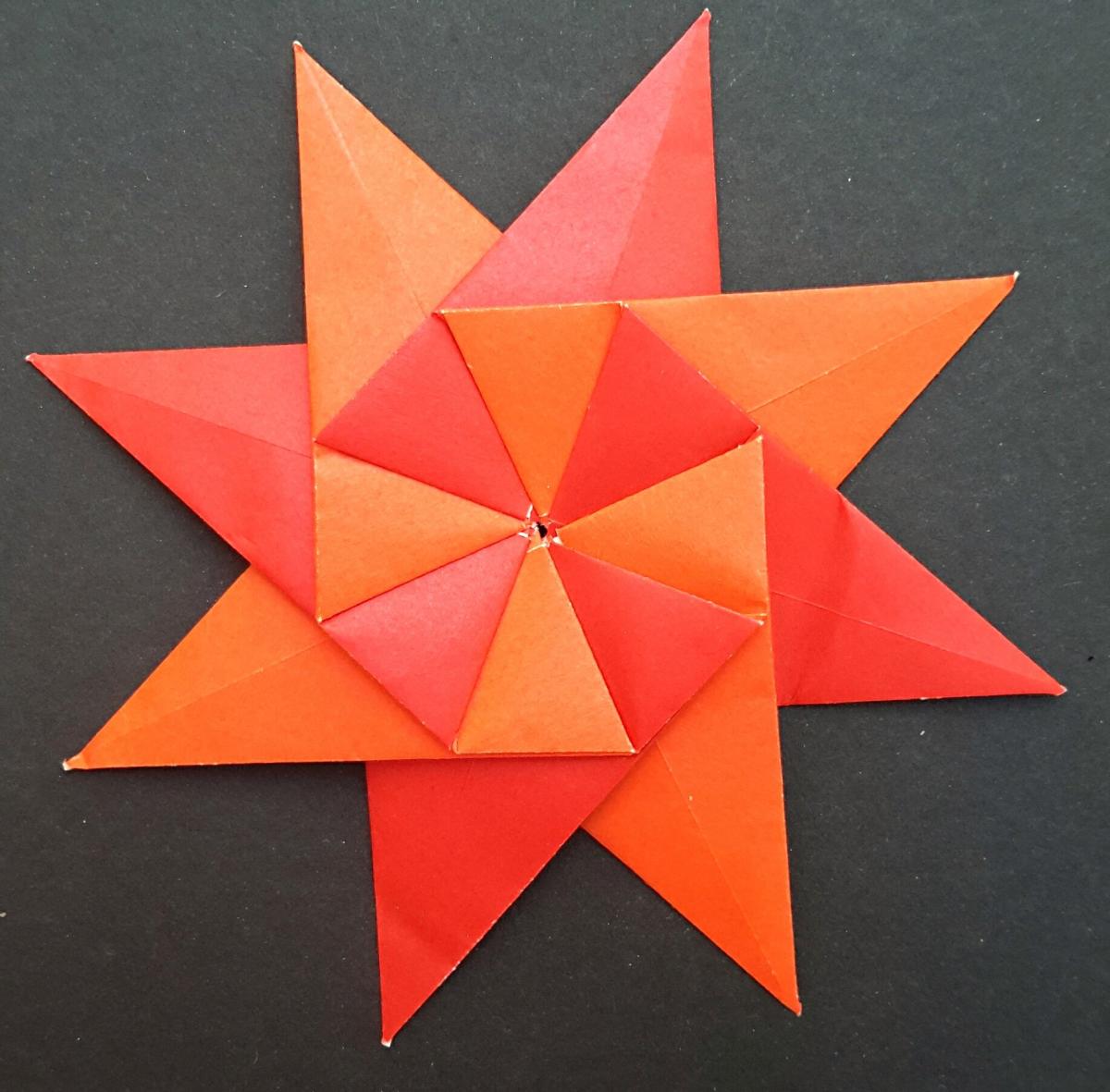 Origami eight pointed star with alternating colors, red and orange. 