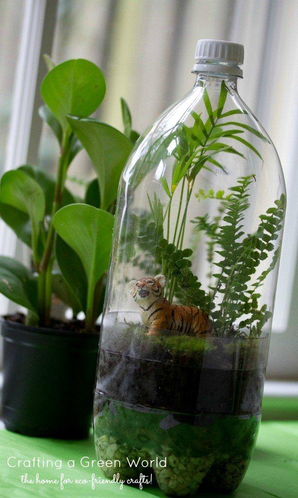 plastic bottle terrarium with plants and plastic tiger in it