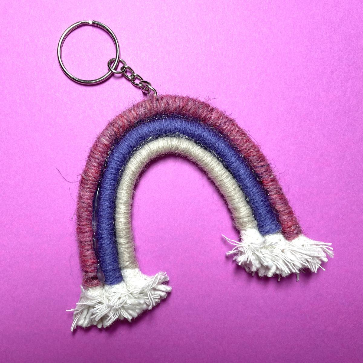 A rainbow made of yarn-covered macrame attached to a keychain. 