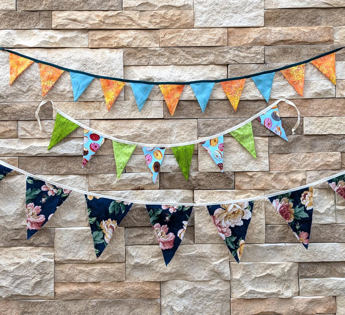three rows of colorful fabric triangles against a stone wall