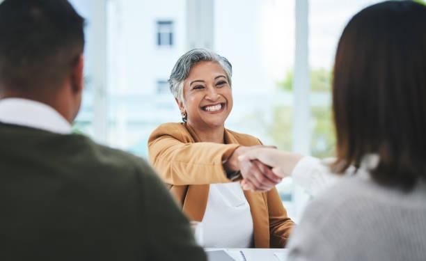 A woman shakes hands with a potential employer at a job interview.
