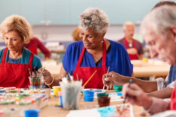 3 seniors seated at table doing a painting project - iStock Royalty Free