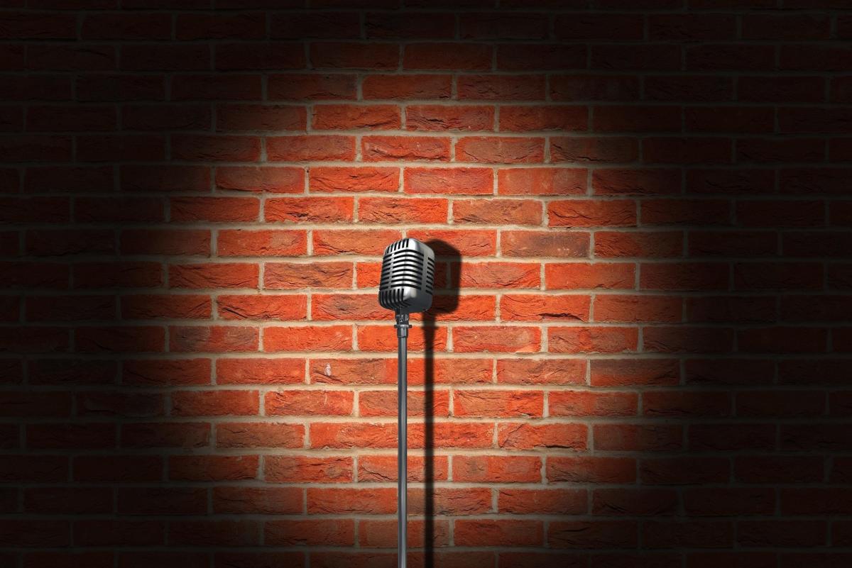 A closeup photo of a microphone onstage with a spotlight being shined on it.