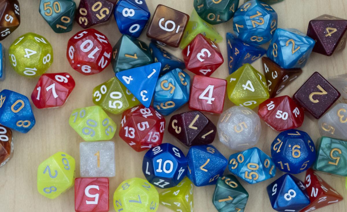 Image depicts a pile of assorted plastic dice, from four-sided to twenty-sided.
