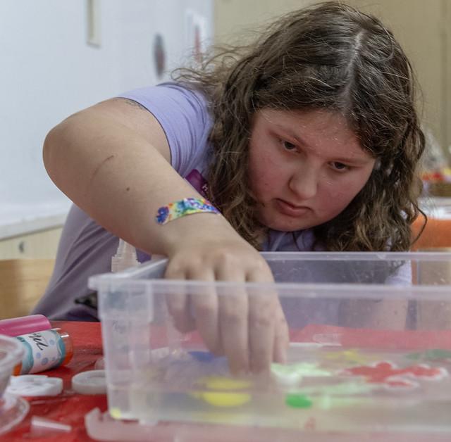 Teen reaching into sensory bin - HCLS Flickr