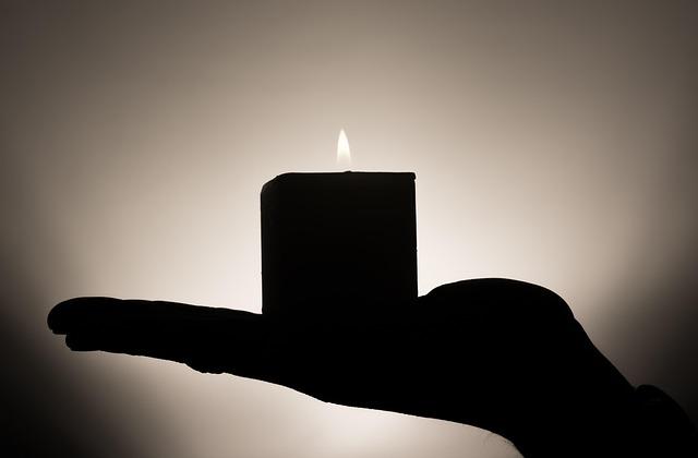 hand holding a candle in silhouette