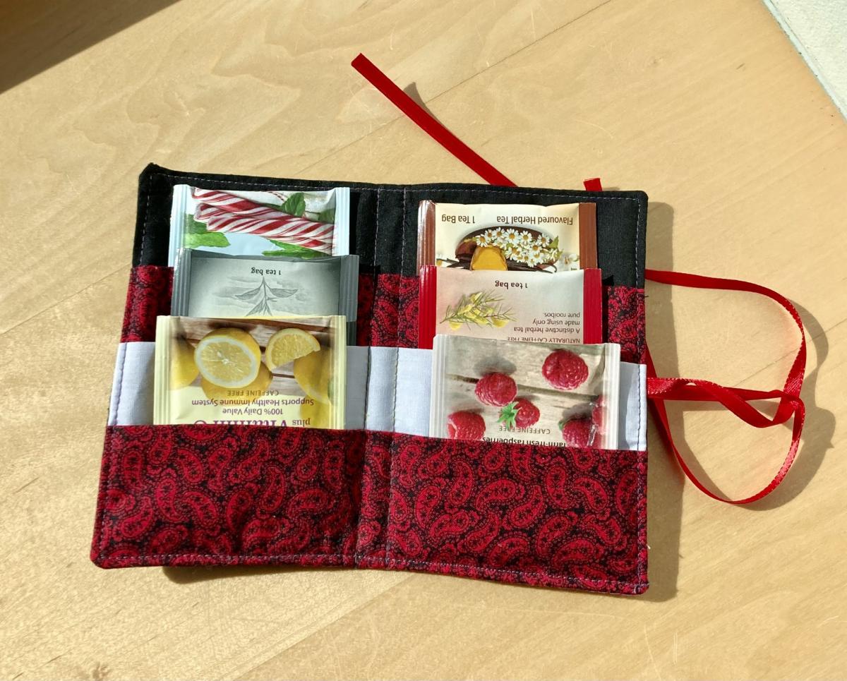 A red and black tea wallet sitting open on a wooden surface