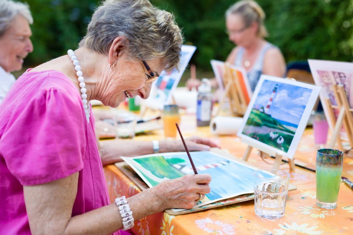 Lady painting a picture at a table outside - Creative Commons